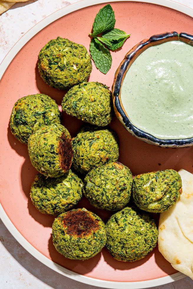 herby baked falafel bites with spicy mint tahini dip on a pink plate with pita
