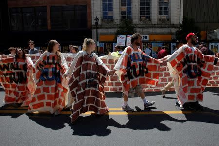 Demonstrators walk in a fake wall during protests outside the Republican National Convention in Cleveland, Ohio, U.S., July 20, 2016. REUTERS/Andrew Kelly