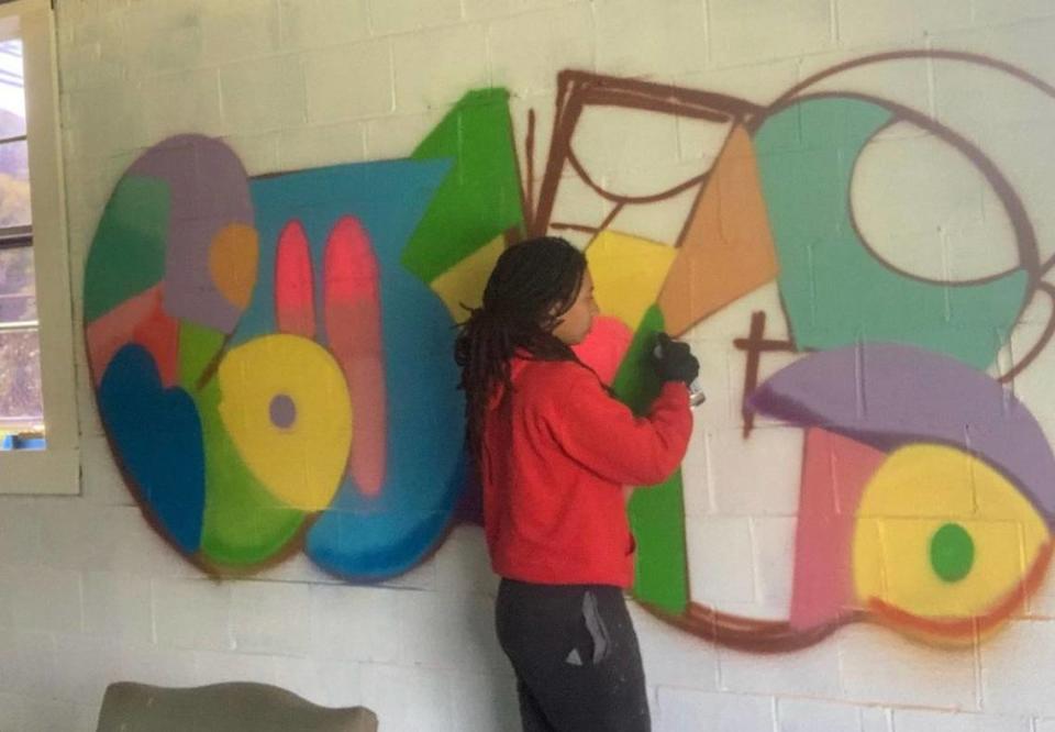 Local artist DeNeer Davis paints a mural in the new space.