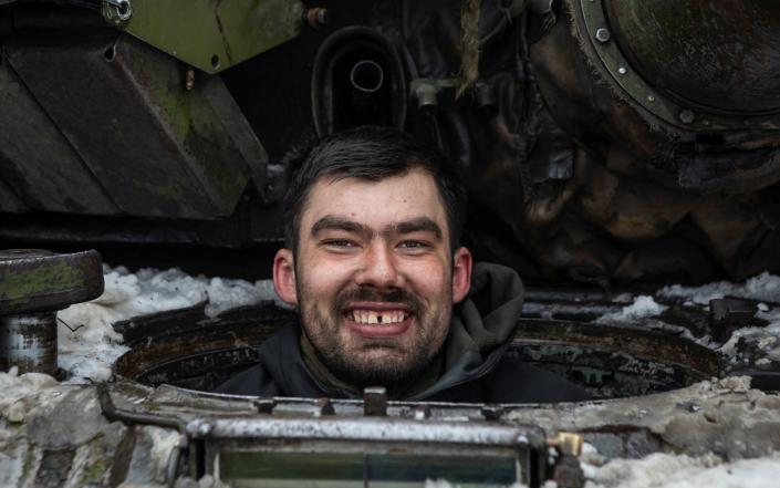 A Ukrainian serviceman smiles as he sits inside a tank outside the frontline town of Bakhmut - STRINGER/REUTERS