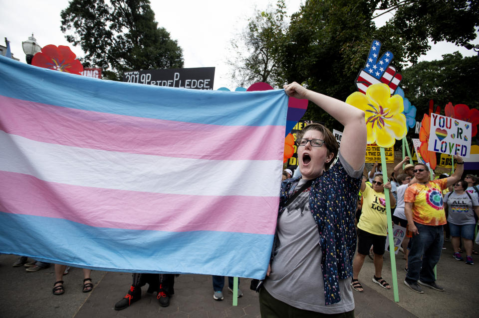 FILE - A supporter for the transgender community holds up a flag in front of counter-protesters at the city's Gay Pride Festival in Atlanta on Oct. 12, 2019. A federal judge in Atlanta has blocked Georgia from enforcing part of a new law that restricts doctors from prescribing hormone therapy to transgender people under the age of 18. Judge Sarah Geraghty granted a preliminary injunction on Sunday, Aug. 20. (AP Photo/Robin Rayne, file)