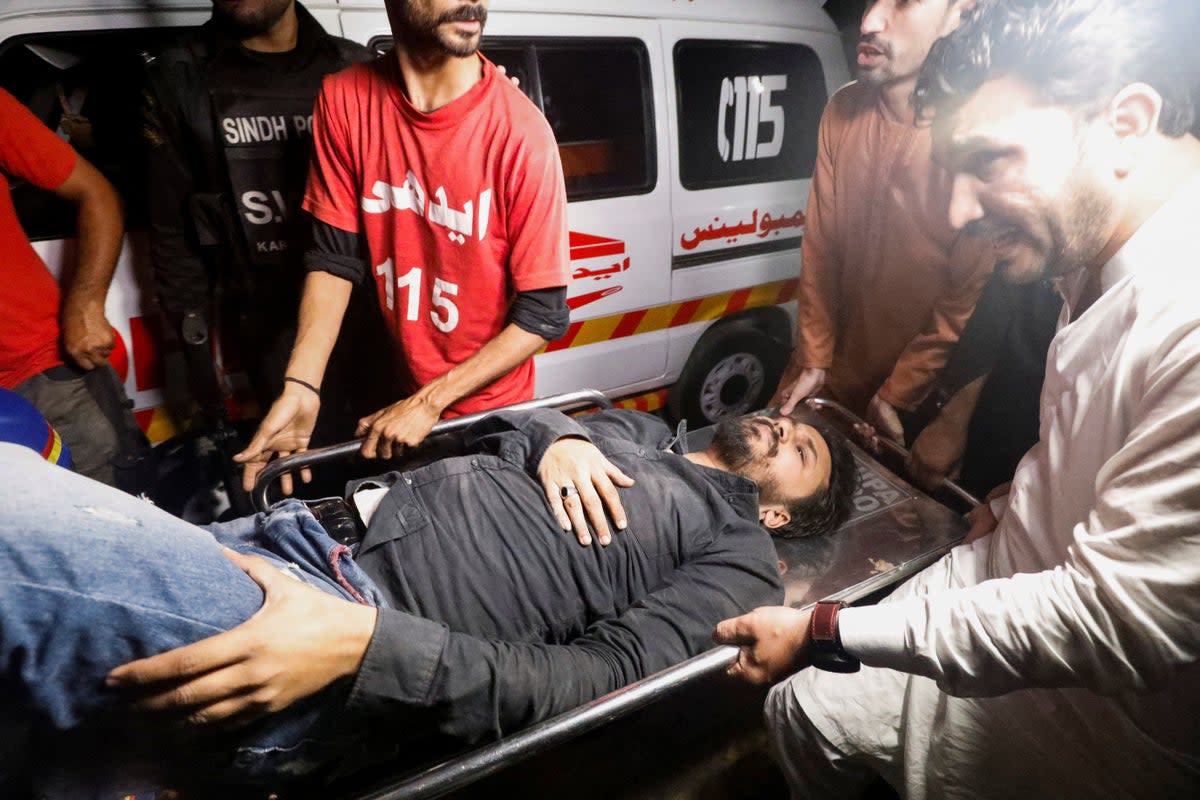 Rescue workers carry an injured person after the attack in Karachi (Reuters)