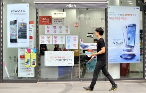 A man walks past signboards of Samsung Electronics' Galaxy S3 (R) and Apple's iPhone 4s (S) at a mobile phone shop in Seoul on August 24, 2012. A Seoul court ruled on August 24, 2012 that Apple and Samsung had infringed on each other's patents on mobile devices, and ordered a partial ban on sales of their products in South Korea