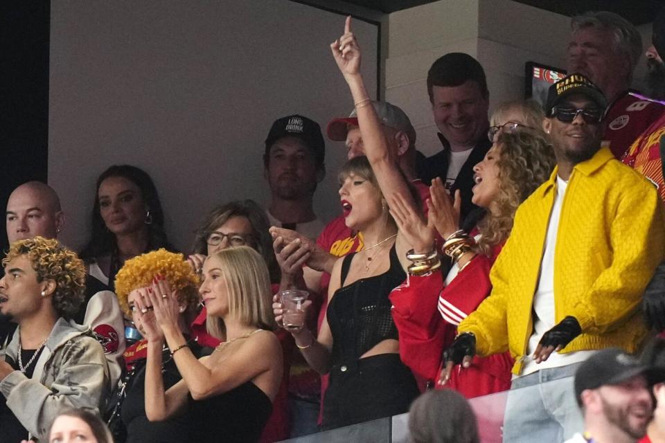 Taylor Swift, centro, hace gestos antes del partido de fútbol americano del