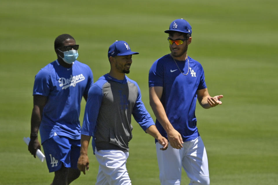 Los Angeles Dodgers right fielder Mookie Betts, center, and center fielder Cody Bellinger, right, chat during the restart of baseball spring training Saturday, July 4, 2020, in Los Angeles. (AP Photo/Mark J. Terrill)