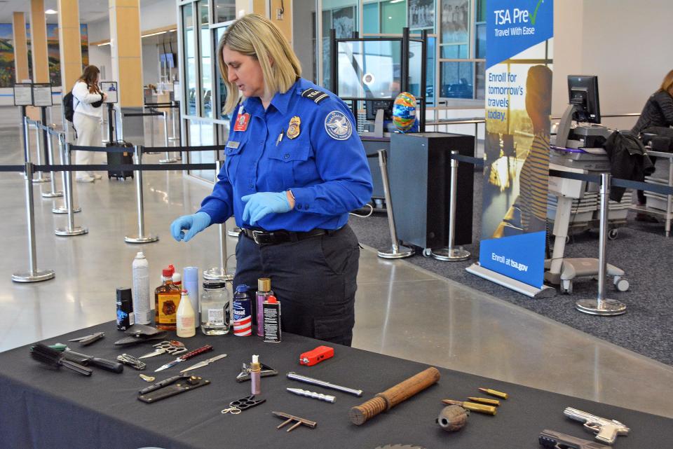 Tracy Holzum, lead transportation security officer the Transportation Security Administration, demonstrates in March 2023 the variety of items confiscated at security checkpoints from airports within Missouri, including at Columbia Regional Airport.