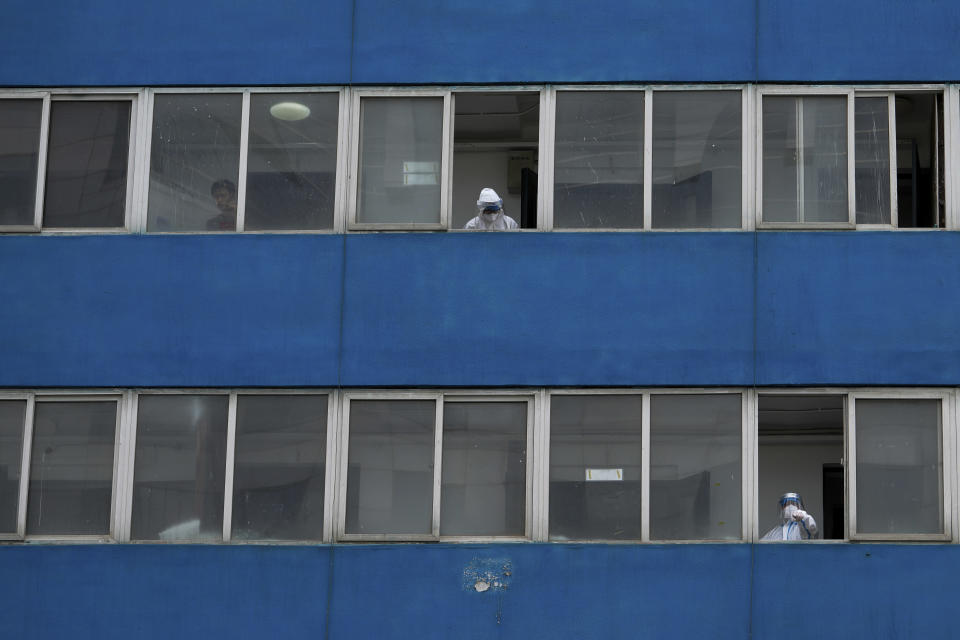 Workers in protection suits watch over a locked down residential complex following a COVID-19 case was detected in the building on Monday, May 9, 2022, in Beijing. (AP Photo/Andy Wong)