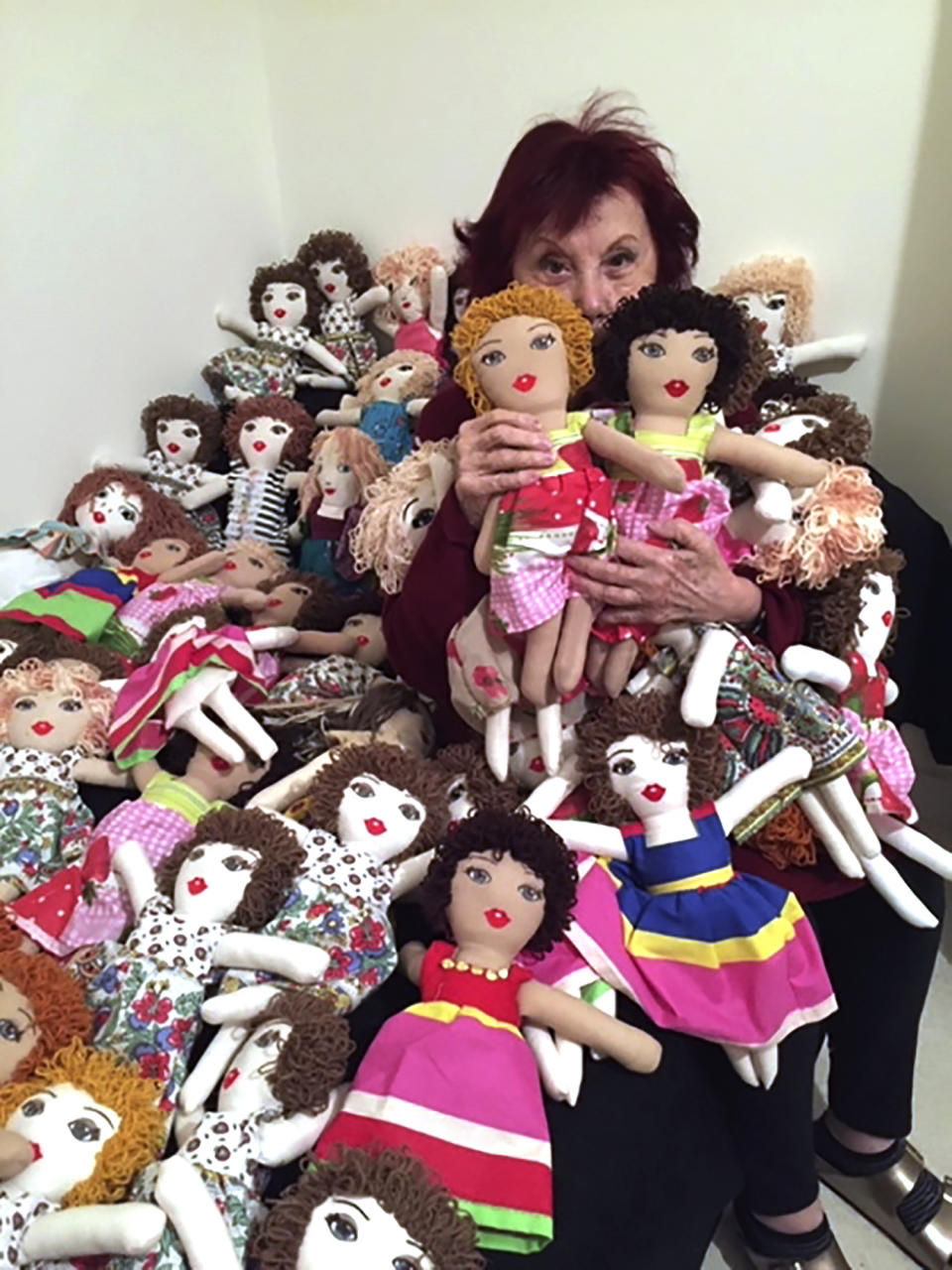 In this photo provided by Lebanese painter Yolande Labaki, Labaki, 93, holds dolls at her house in Beirut, Lebanon, Monday, Nov. 16, 2020, that she made to be distributed to children who might have lost their toys amid the destruction or who had otherwise had their lives touched by the Beirut seaport blast in August 2020. After the massive explosion devastated Beirut, Labaki made 100 dolls for children affected by the destruction. (Yolande Labaki via AP)