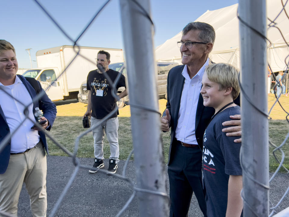 Michael Flynn, a retired three-star general who served as President Donald Trump’s national security advisor, gives a thumbs-up as he poses for a photograph with a young supporter outside the tent during the ReAwaken America Tour at Cornerstone Church in Batavia, N.Y., Friday, Aug. 12, 2022. (AP Photo/Carolyn Kaster)