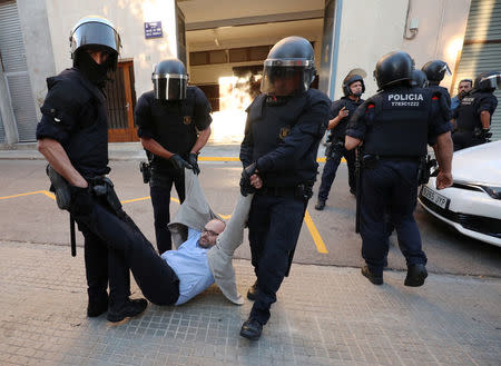 Catalan police officers remove a protestor from the street outside a Unipost office which was raided in search of material for the proposed October 1 referendum, in Terrassa, Spain, September 19, 2017. REUTERS/Albert Gea