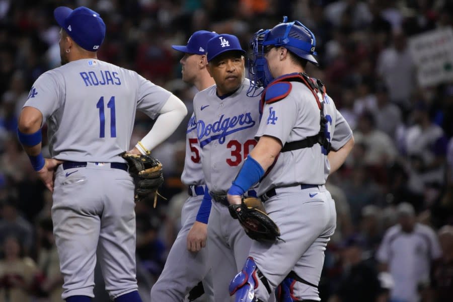 Los Angeles Dodgers manager Dave Roberts, center, talks with catcher Will Smith, right, during a pitching change in the third inning in Game 3 of a baseball NL Division Series against the Arizona Diamondbacks, Wednesday, Oct. 11, 2023, in Phoenix. (AP Photo/Rick Scuteri)