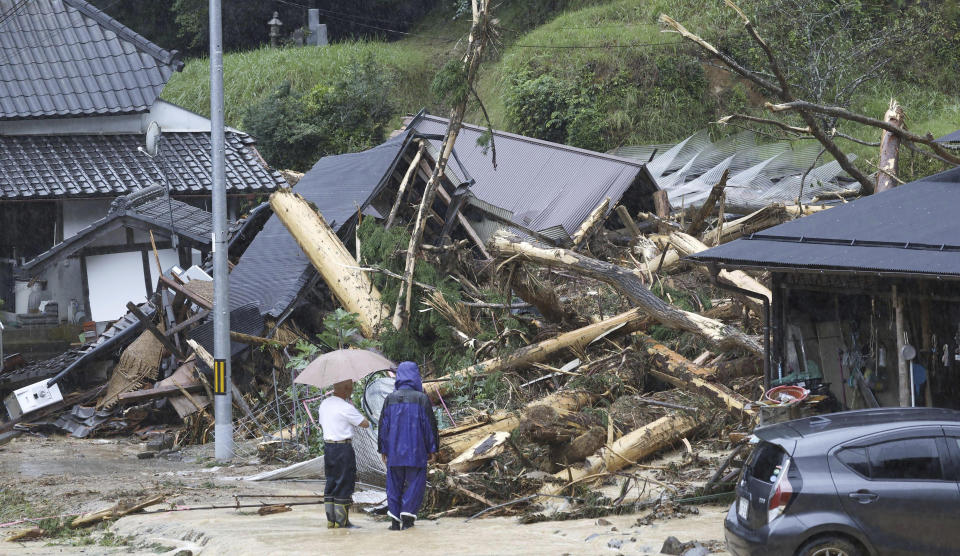 People stand by a mudslide site following a storm in Ayabe, Kyoto prefecture, western Japan Tuesday, Aug. 15, 2023. A strong tropical storm lashed central and western Japan with heavy rain and high winds Tuesday, causing flooding and power blackouts and paralyzing air and ground transportation while many people were traveling for a Buddhist holiday week. (Kyodo News via AP)