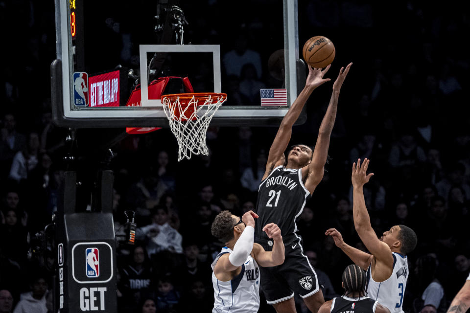 Brooklyn Nets' Noah Clowney (21) reaches for the ball over Dallas Mavericks forward Grant Williams (3) and center Dwight Powell, left, during the first half of an NBA basketball game in New York, Tuesday, Feb. 6, 2024. (AP Photo/Peter K. Afriyie)