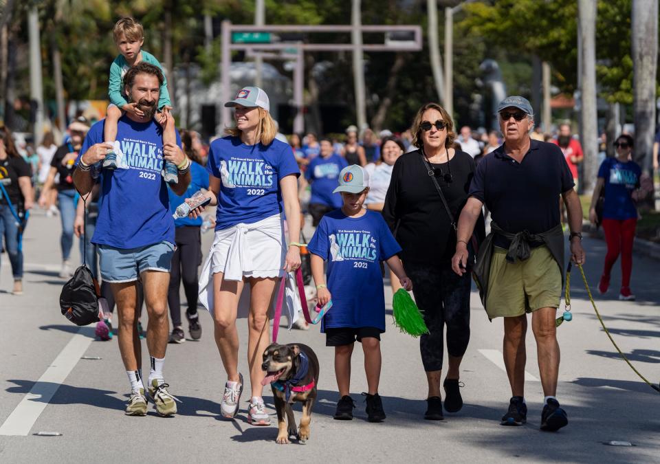 People walk their dogs along Flagler Drive during the Peggy Adams Animal Rescue League's 21st Annual Walk for the Animals in West Palm Beach, Florida on February 19, 2022.