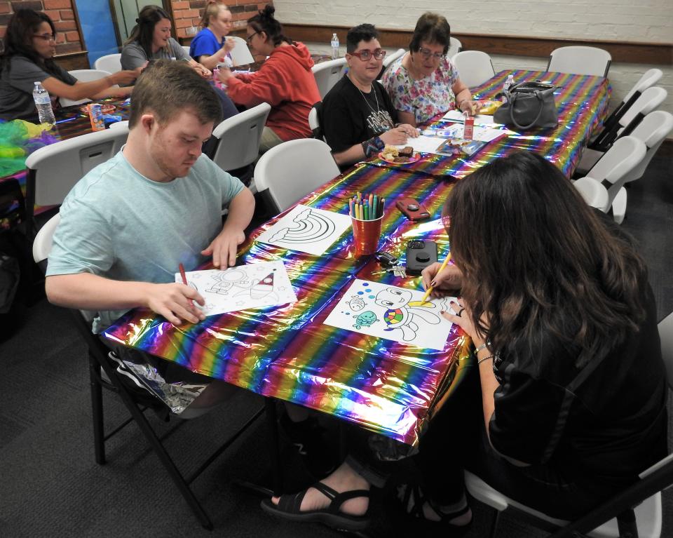 Scott Balentine and Toby Collins, recreation and Special Olympics manager for the Coshocton County Board of Developmental Disabilities, color pictures for the Library for All program at the Coshocton County District Library for adults with disabilities and their family and friends. It started last summer.