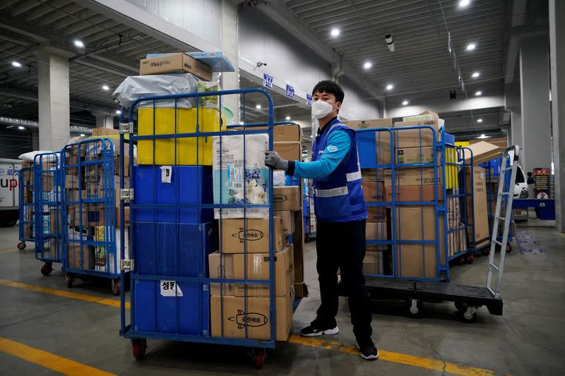 A delivery man for Coupang Jung Im-hong wearing a mask to prevent contracting the coronavirus, loads packages before leaving to deliver them in Incheon