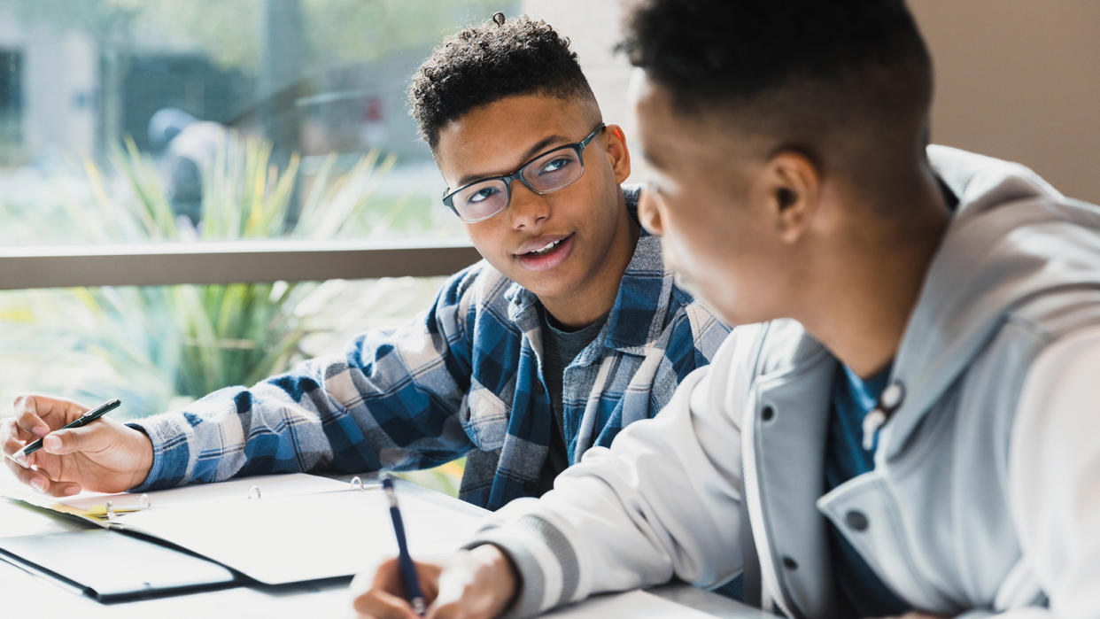 A teenager talks to his friend as they study together