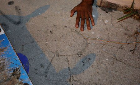 Thiago Sousa touches a flower drawn in wet concrete by Israel Hernandez-Llach in the Wynwood arts district in Miami, Florida, U.S., on December 1, 2016. REUTERS/Joe Skipper/Files