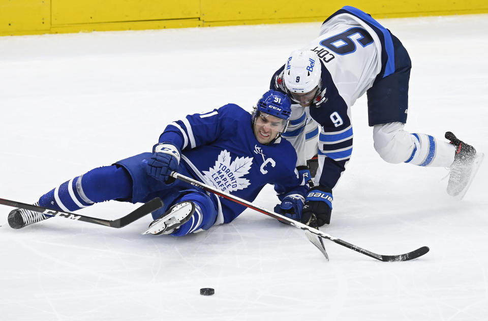 Toronto Maple Leafs center John Tavares (91) becomes entangled with Winnipeg Jets center Andrew Copp (9) during first-period NHL hockey game action in Toronto, Saturday, March 13, 2021. (Frank Gunn/The Canadian Press via AP)