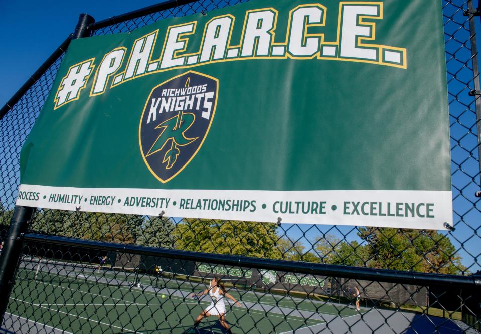 Richwoods sophomore tennis player Theresa Bartelme makes a return during a Sept. 29, 2022 match against Bloomington High School at the Richwoods tennis courts. A giant banner with the acronym #P.H.E.A.R.C.E. hangs on the fence at the entrance to the courts.