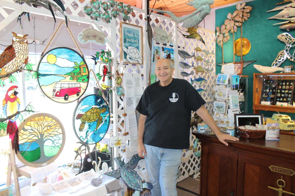 Dennis Del Prete, owner of Dunes Mercantile, a gift shop and guitar bar located in the 8600 block of East Oak Island Drive, shows off some of his stained glass work on July 28, which along with work by other local artists, is for sale in the shop.