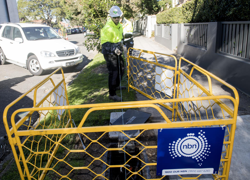 An NBN contractor can be seen laying fibre cable in a ditch in Sydney.