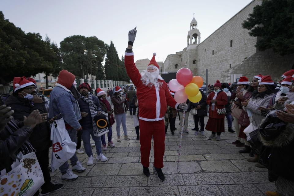 A man dressed as Santa Claus dances outside the Church of the Nativity, traditionally believed to be the birthplace of Jesus Christ, on Christmas Day in the West Bank city of Bethlehem, Saturday, Dec. 25, 2021. The biblical town of Bethlehem is gearing up for its second straight Christmas hit by the coronavirus with small crowds and gray, gloomy weather dampening celebrations Saturday in the traditional birthplace of Jesus. (AP Photo/Majdi Mohammed)