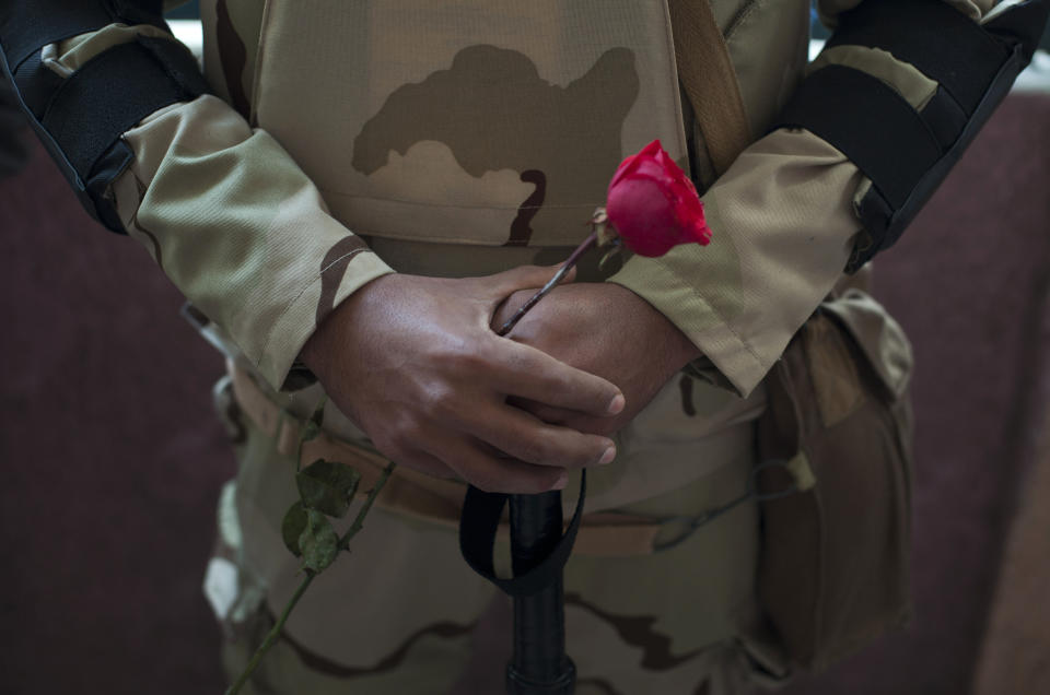 An Egyptian army soldier holds a red rose as he stands guard a polling station during the vote in the country's constitutional referendum in Cairo, Egypt, Tuesday, Jan. 14, 2014. Upbeat and resentful of the Muslim Brotherhood, Egyptians voted Tuesday on a new constitution in a referendum that will pave the way for a likely presidential run by the nation's top general months after he ousted Islamist President Mohammed Morsi.(AP Photo/Khalil Hamra)