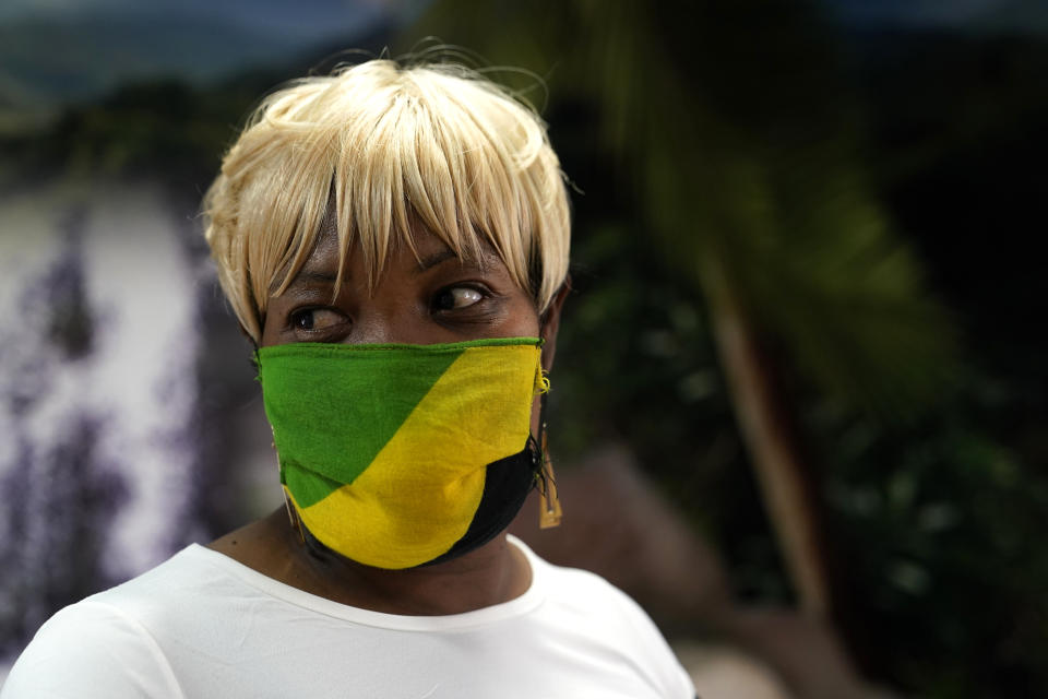 In this Aug. 26, 2020, photo Sophia Ball wears a protective face covering in the colors of the Jamaican flag as she picks up her order at the Dutch Pot Jamaican Restaurant in Pembroke Pines, Fla. Voters in the Democratic stronghold of Broward County, which includes Pembroke Pines and Fort Lauderdale, are eager to defeat Trump, but say they are even more energized to turn out in support of California Sen. Kamala Harris, Biden’s running mate whose father is Jamaican. (AP Photo/Lynne Sladky)