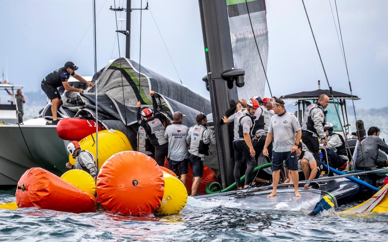 Crew from the United States' American Magic boat Patriot and Team New Zealand attempt to keep Patriot afloat after it capsized - AP