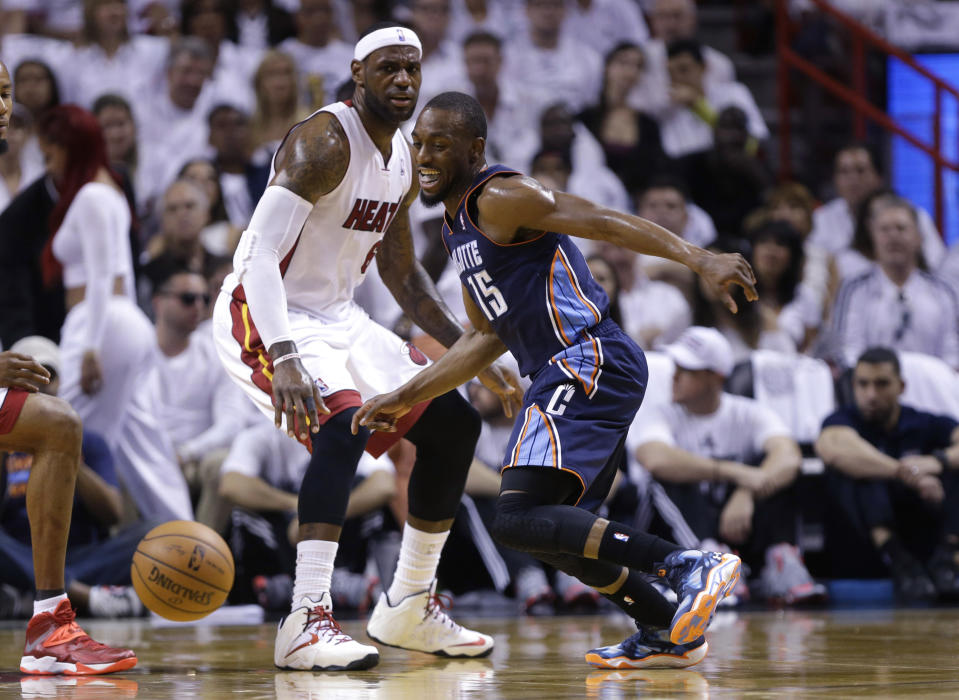 Charlotte Bobcats' Kemba Walker (15) and Miami Heat's LeBron James (6) eye a loose ball during the first half in Game 1 of an opening-round NBA basketball playoff series, Sunday, April 20, 2014, in Miami. (AP Photo/Lynne Sladky)