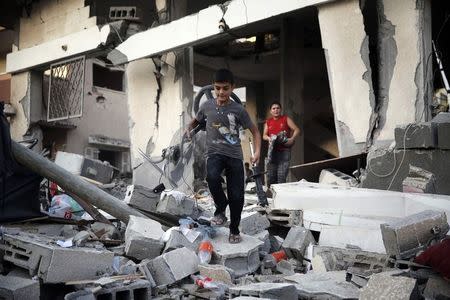 Palestinian boys salvage belongings from a damaged home, which police said was targeted in an Israeli air strike, in Gaza City July 17, 2014. REUTERS/Finbarr O'Reilly