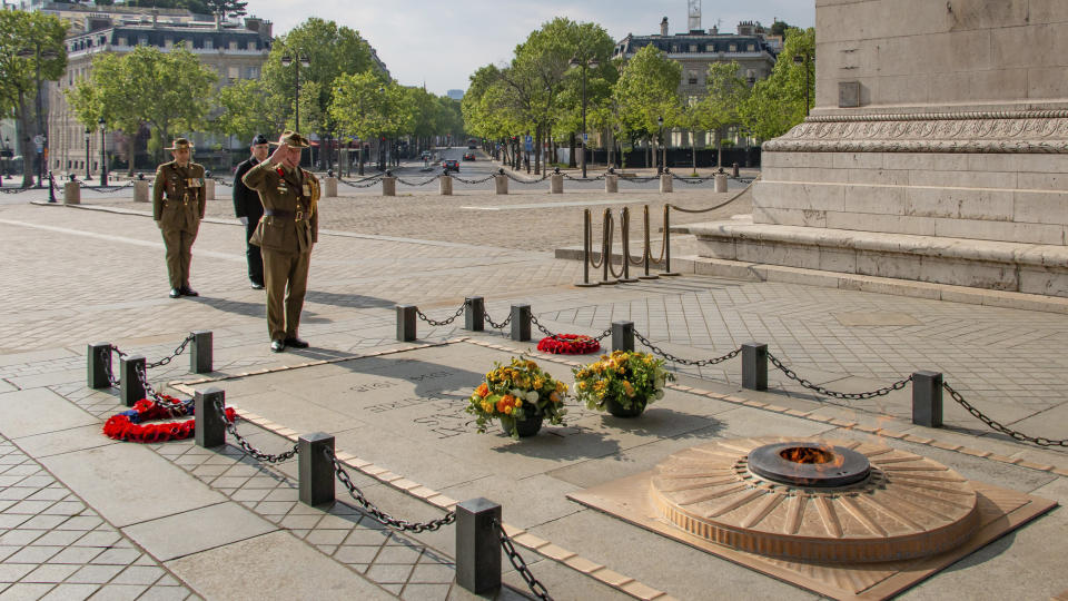 This photo provided by the Australian Embassy in Paris, shows Australian Defense Attache to France Colonel Joel Dooley and ADF members paying their respects at the tomb of the unknown soldier beneath the Arc de Triomphe in Paris, Saturday April 25, 2020, on the occasion of Anzac Day. With France in coronavirus lockdown, there were no crowds to mark ANZAC Day, a national day of remembrance in Australia and New Zealand for those who served in all wars. (Simon Patching/Australian Embassy in France via AP)