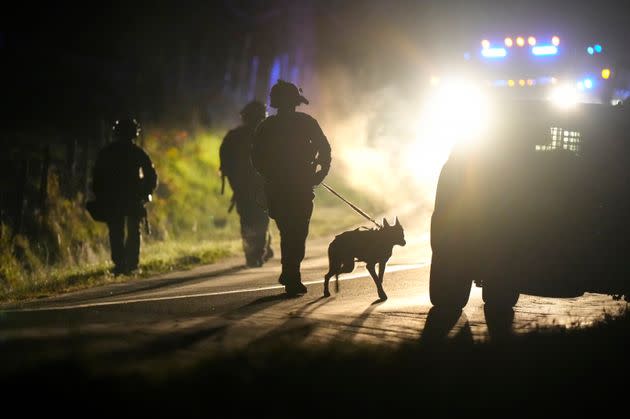 A member of law enforcement walks with a police dog outside a property on Meadow Road in Bowdoin, Maine, Thursday, Oct. 26, 2023. Hundreds of heavily armed police and FBI agents searched intensely for Robert Card, an Army reservist authorities say fatally shot a number of people at a bowling alley and a bar Wednesday. 