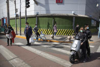 People pause at an intersection during a national moment of mourning for victims of coronavirus in Beijing, Saturday, April 4, 2020. With air raid sirens wailing and flags at half-staff, China on Saturday held a three-minute nationwide moment of reflection to honor those who have died in the coronavirus outbreak, especially "martyrs" who fell while fighting what has become a global pandemic. (AP Photo/Mark Schiefelbein)