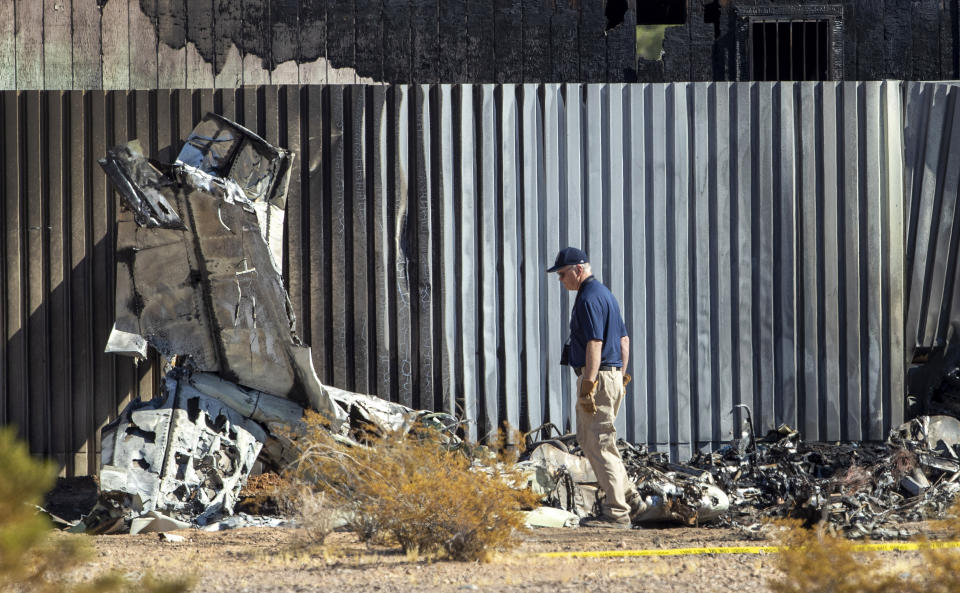 An investigator looks at the site of a deadly plane crash Thursday, Oct. 29, 2020, in Las Vegas. A twin-engine aircraft crashed shortly after takeoff Thursday, killing two people and igniting a fire that damaged a construction trailer from which a man escaped while choking on fuel fumes. (Steve Marcus/Las Vegas Sun via AP)