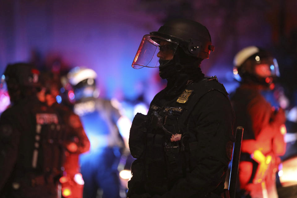 FILE - A Portland Police officer watches protesters rallying at the Mark O. Hatfield United States Courthouse on Sept. 26, 2020, in Portland, Ore. An Oregon lawmaker has introduced a bill that would require law enforcement officers complete at least two years of postsecondary education. The bill would push back against the recent trend of lowering police hiring standards by requiring two years of postsecondary education for departments with less than 50 officers and a bachelor's degree for departments with more than 50. (AP Photo/Allison Dinner, File)