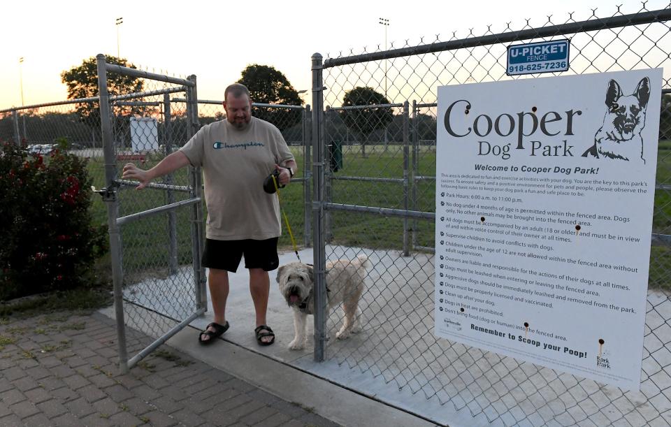 Kelly Grayum and his soft-coated Wheaten Terrier, "Willie Nelson", leave the Cooper Dog Park after some brief exercise recently at dusk in Bartlesville.