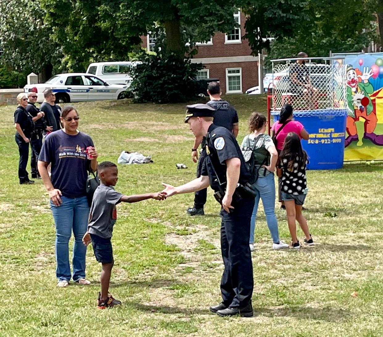 Worcester Police Lt. Sean Murtha exchanges a high-five with Dylan and his mother, Jana Bromell, during the department's inaugural Back-to-School Bash and Community Party on Saturday at Institute Park.