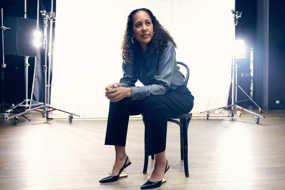 A woman with long hair sits in a chair.