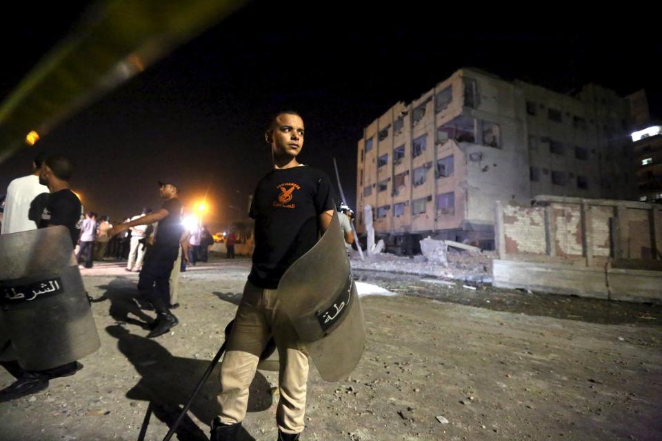 Security officials stand guard at the site of a bomb blast at a national security building in Shubra Al-Khaima, on the outskirts of Cairo, Egypt