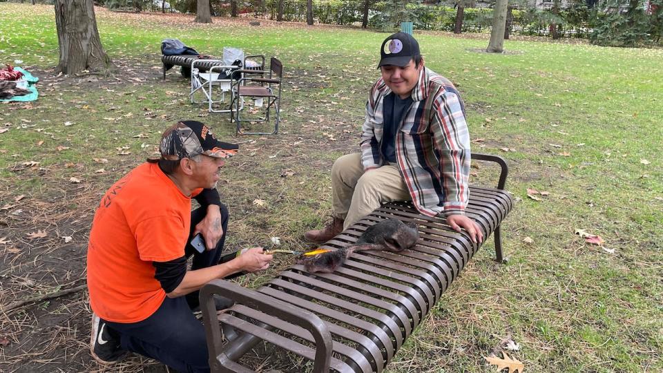 Left, William Coonishish teaches his grandson, right, Malick Duff how to scorch a moose nose with a propane cylinder.