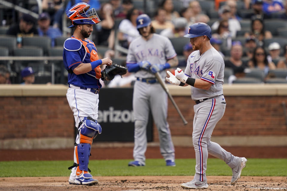 Texas Rangers' Kole Calhoun, right, runs home to score past New York Mets catcher Tomas Nido, left, after hitting a three-run home run off starting pitcher Trevor Williams (29) in the second inning of a baseball game, Saturday, July 2, 2022, in New York. (AP Photo/John Minchillo)