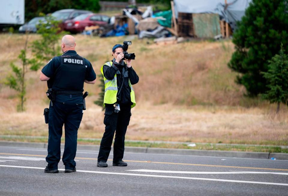 An officer and crime scene technician investigate a drive by shooting at the intersection of South Tacoma Way and South 47th Street in Tacoma, Wash. on Sunday, July 3, 2022. An adult male was shot in a vehicle and transported to the hospital with serious injuries, according to the Tacoma Police Department.