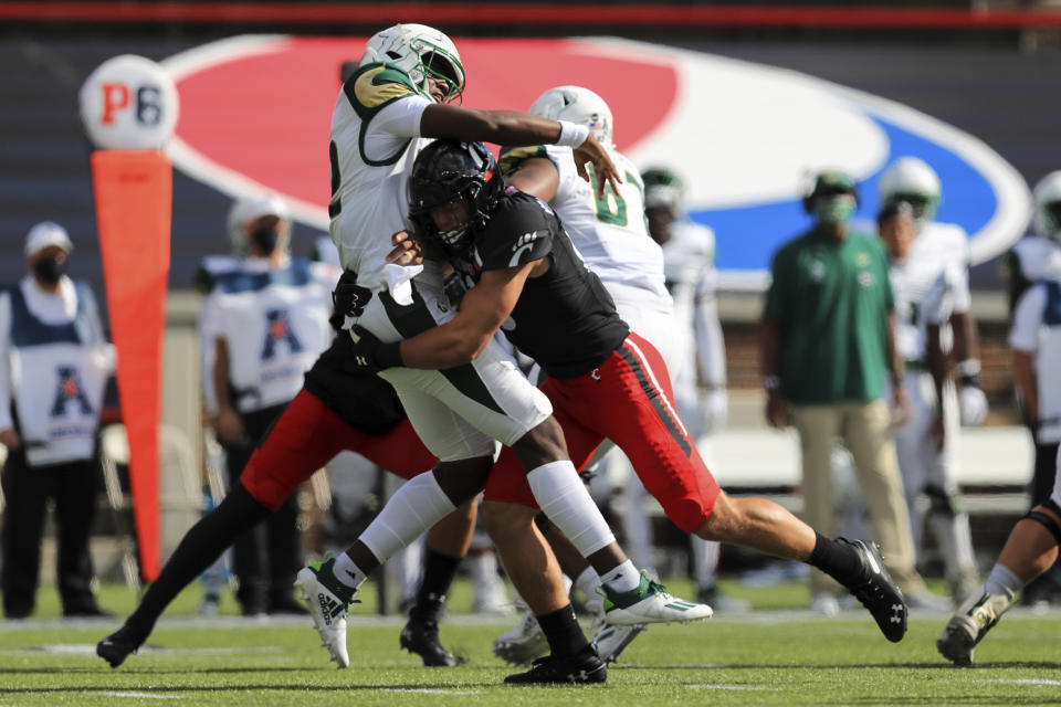 South Florida quarterback Katravis Marsh, left, throws as he is hit by Cincinnati linebacker Ty Van Fossen, right, during the first half of an NCAA college football game, Saturday, Oct. 3, 2020, in Cincinnati. (AP Photo/Aaron Doster)