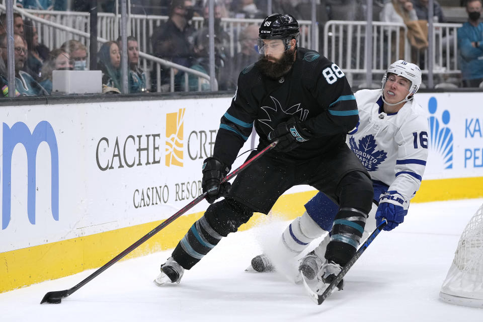 San Jose Sharks defenseman Brent Burns (88) moves the puck past Toronto Maple Leafs center Mitchell Marner (16) during the second period of an NHL hockey game Friday, Nov. 26, 2021, in San Jose, Calif. (AP Photo/Tony Avelar)
