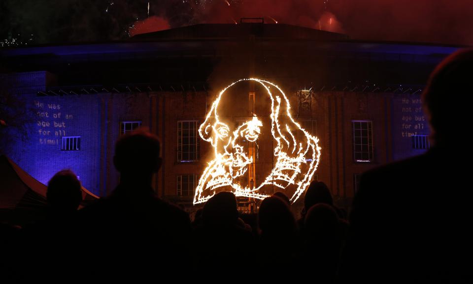 People look at flaming depiction of William Shakespeare during a firework display at Royal Shakespeare Company marking 450th anniversary of Shakespeare's birth in Stratford-upon-Avon