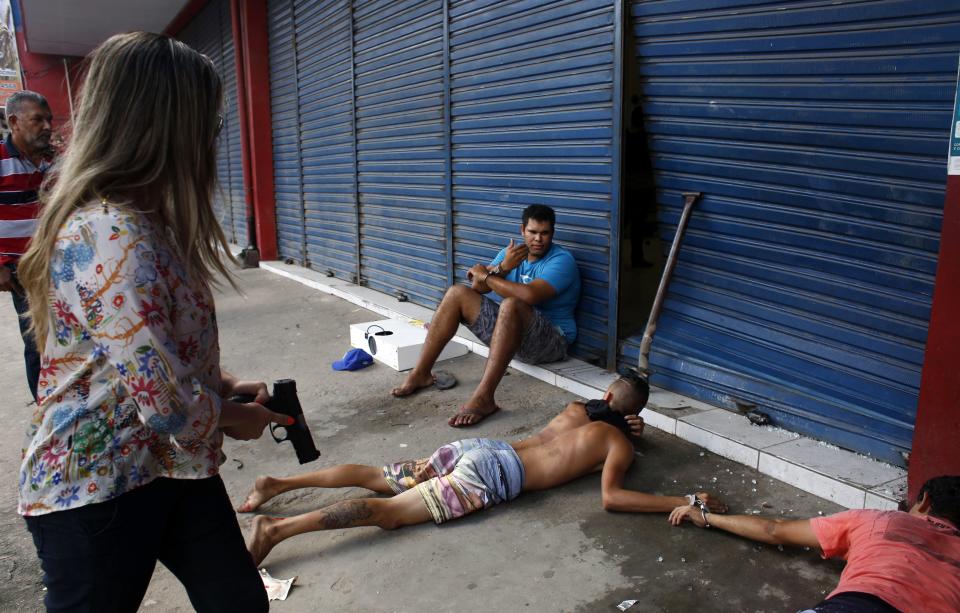 Civil police officer detain young suspects after a store was looted during a police strike in Recife