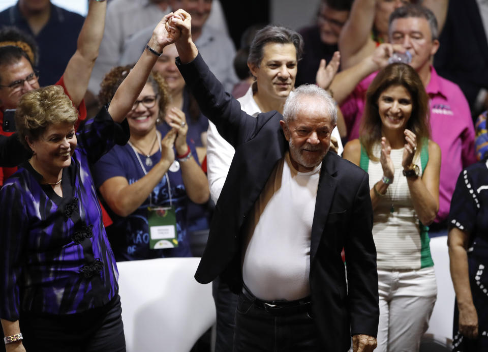 Former Brazilian President Luiz Inacio Lula da Silva, center, and former Brazilian president Dilma Rousseff raise their arms during the Workers' Party 7th Congress, in Sao Paulo, Brazil, Friday, Nov. 22, 2019. Da Silva is the unquestioned star of the PT 3-day party convention. Many still think he could be the party's standard-bearer once again in 2022 - when he'll be a 77-year-old cancer survivor who is now barred from seeking office due to a corruption conviction. (AP Photo/Nelson Antoine)