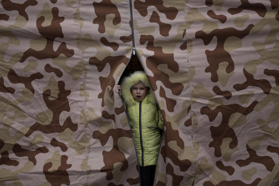 A child looks from a tent after crossing from Ukraine in Medyka, Poland, Wednesday, March 9, 2022. (AP Photo/Daniel Cole)